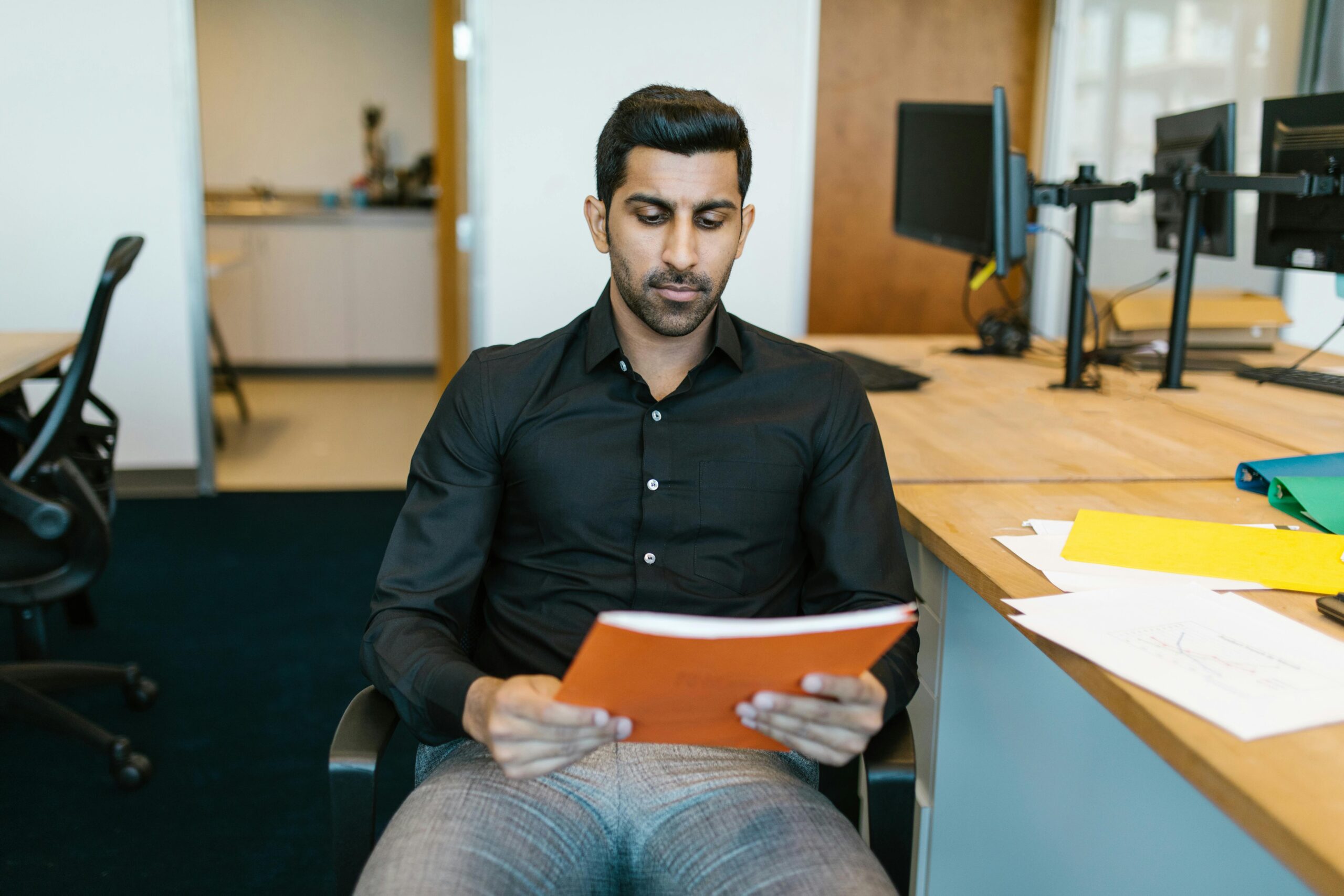 Serious businessman reviewing a document while sitting in a modern office.